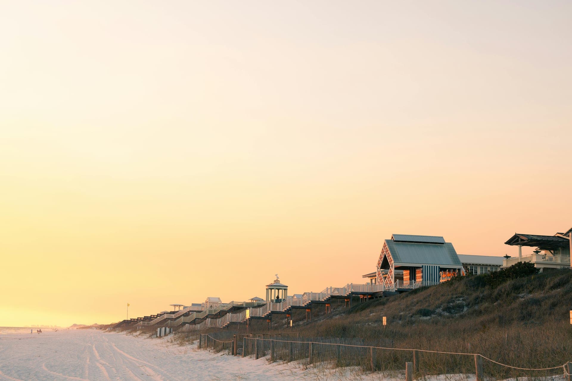A row of Emerald Coast beach houses at golden hour above the sugar-white sand — documented visit after visit, between stays.