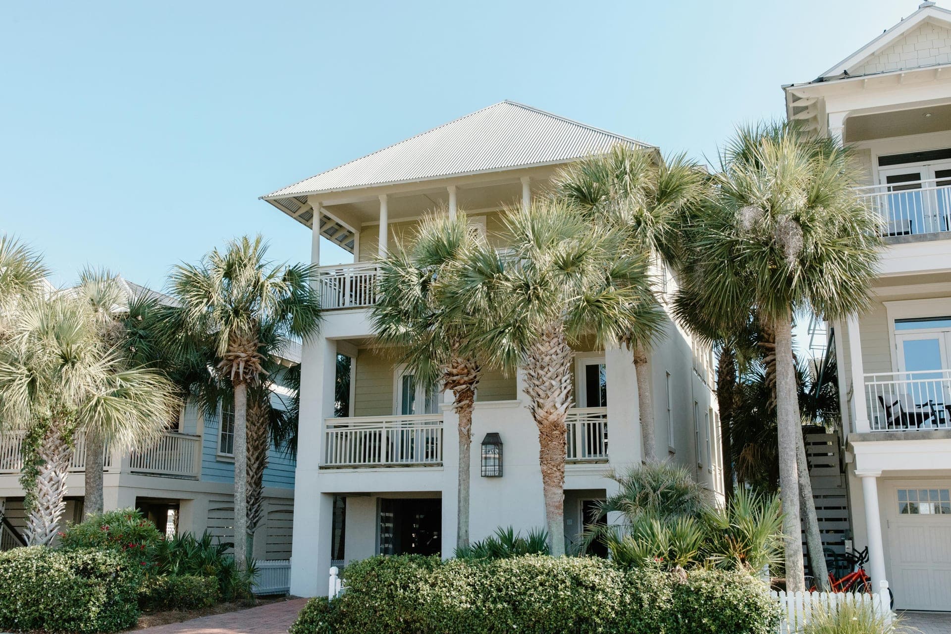 A three-story white coastal beach house framed by tall palms — the kind of rental I walk top to bottom.