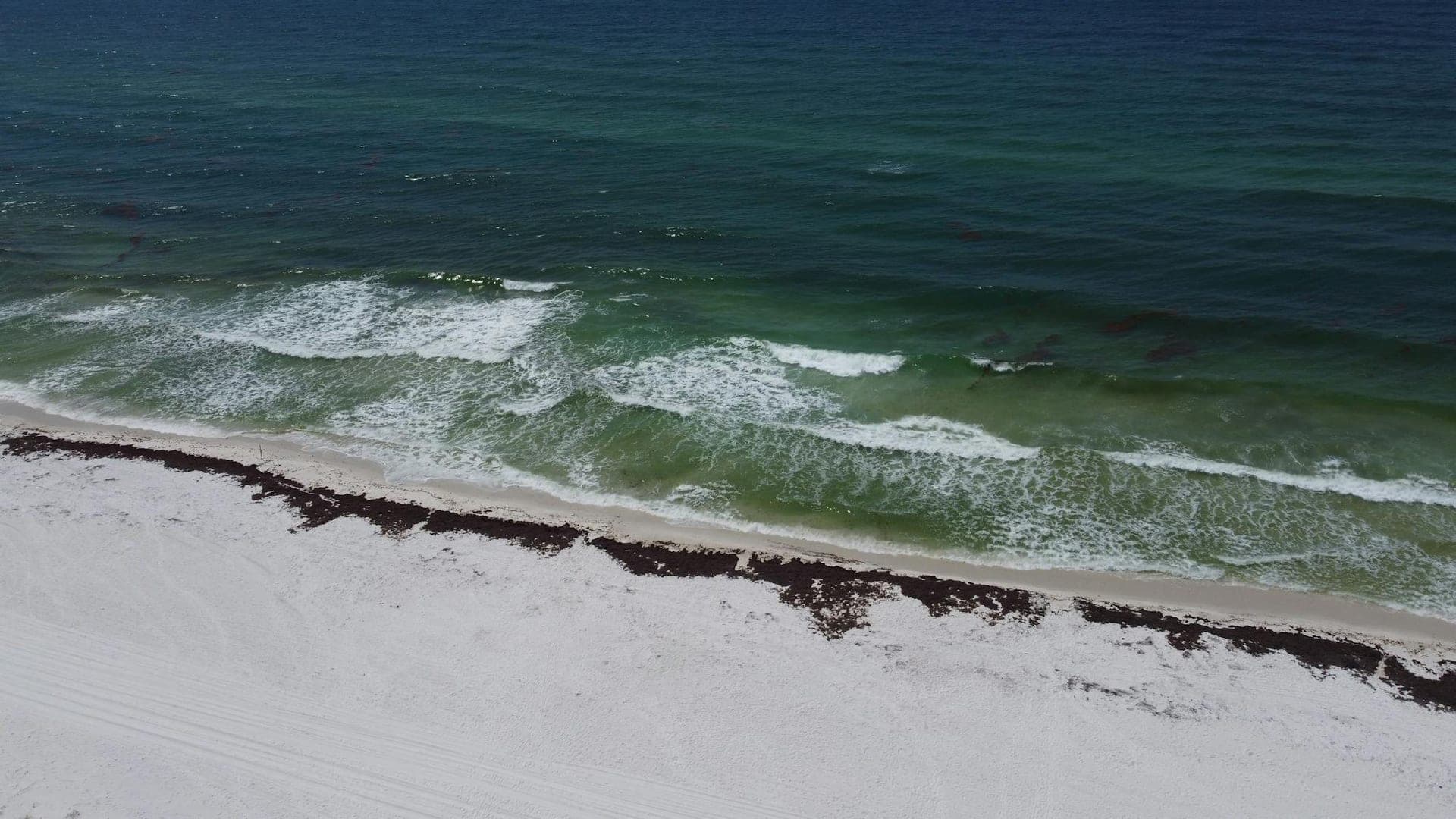 Aerial view of Pensacola Beach — white sand fronting the turquoise Gulf along Florida's Emerald Coast.