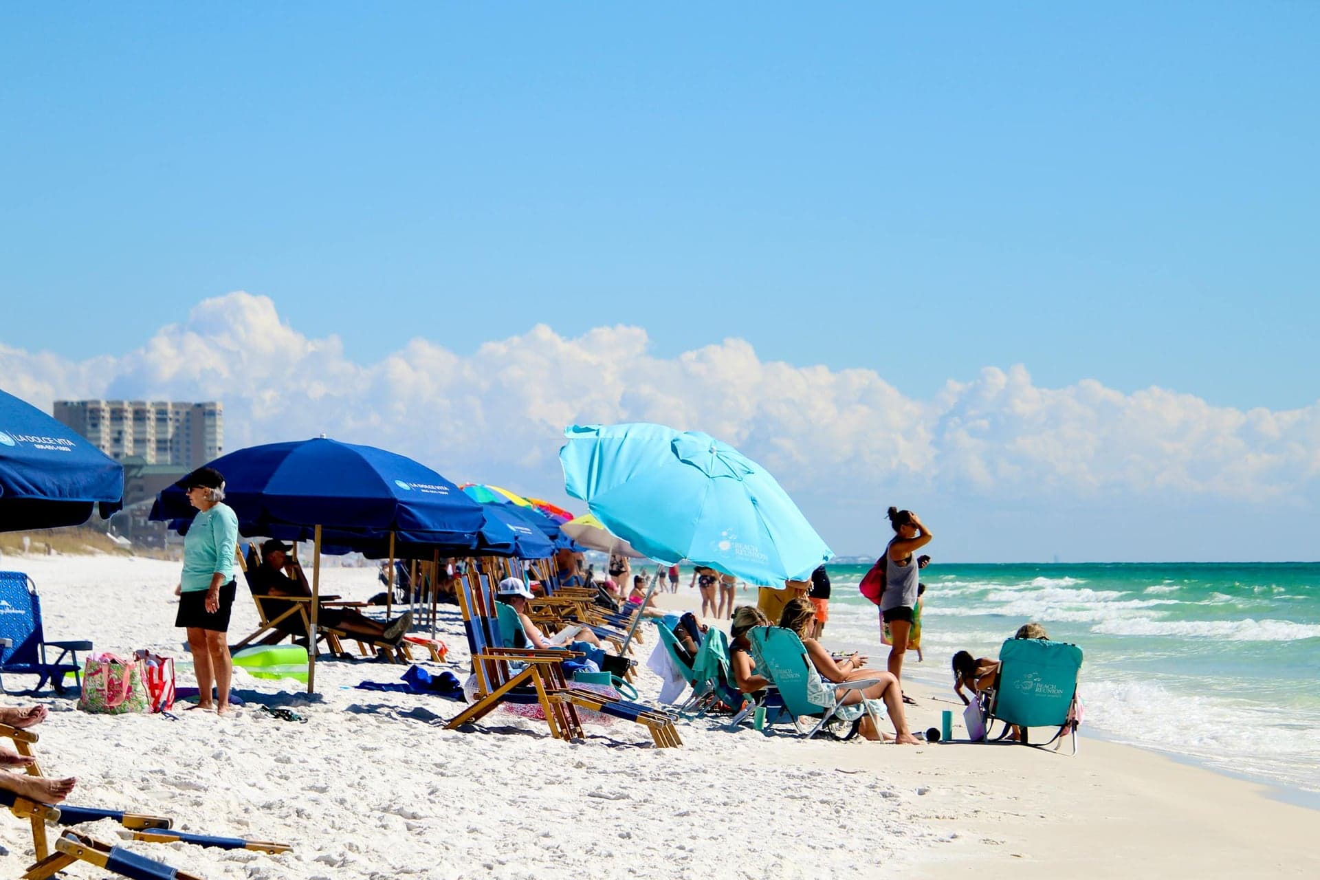 Beach umbrellas and chairs lined along the white sand beside the emerald Gulf water near Navarre Beach.